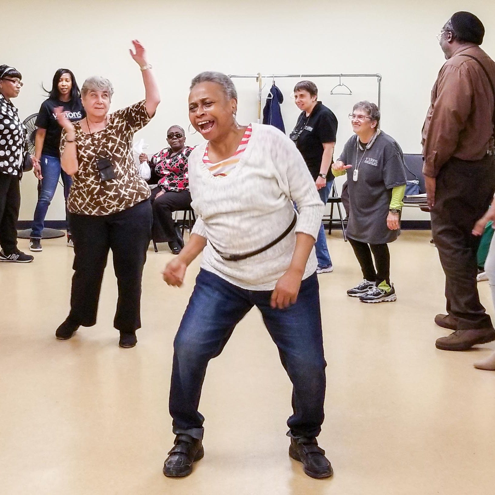 Photo of a group of older adults dancing in a large room.