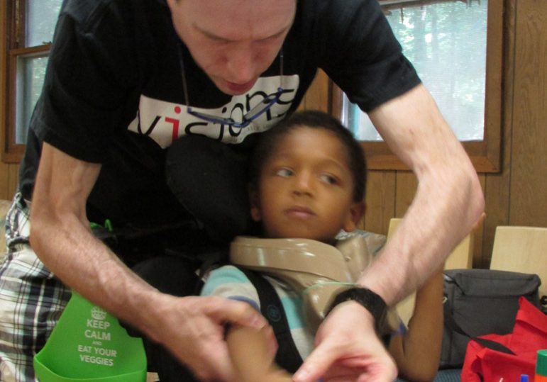 guy with white hair and skinny arms helping young boy with dexterity exercises