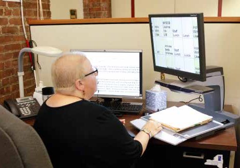 Lady working dual monitors on her small desk