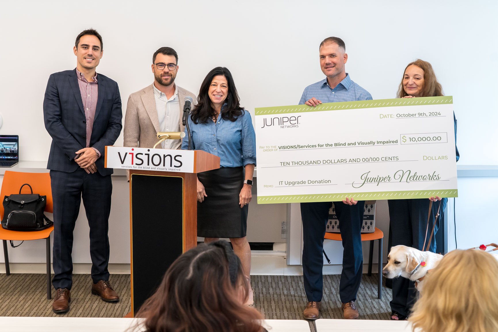 Photo of Juniper Networks and VISIONS staff standing together as two VISIONS staff hold a large $10,000 check.