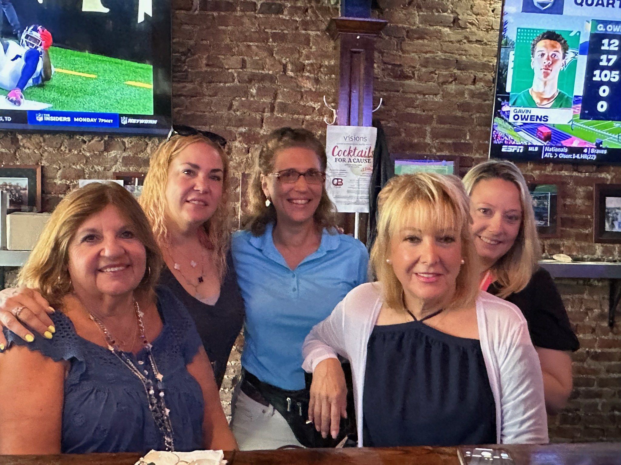 Photo of a group of Queens Advisory Board members standing at a long table and smiling to the camera.